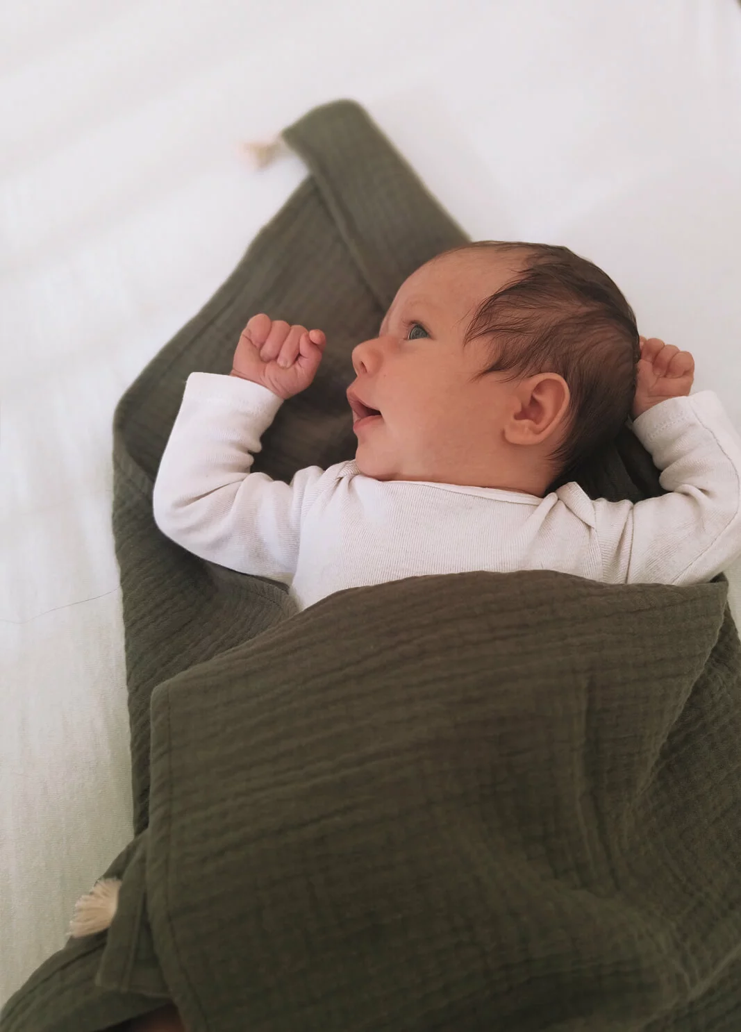 Bébé dort paisiblement sur un lange en gaze de coton bio.